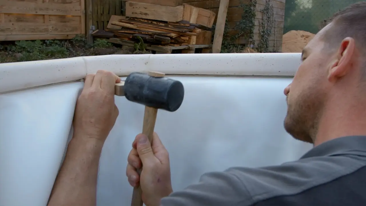 Dichtungsgummi in das Einhängeprofil der Poolabhängung mit Keil und Gummihammer fixieren