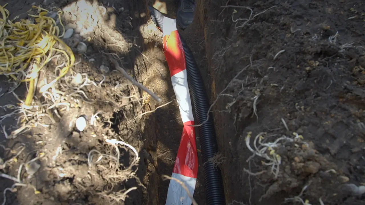 Leerrohr für Strom zum Poolfilter im Graben mit Gefahrenband