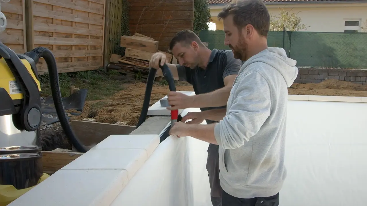 Schlauch des Industriestaubsaugers hinter Poolfolie schieben